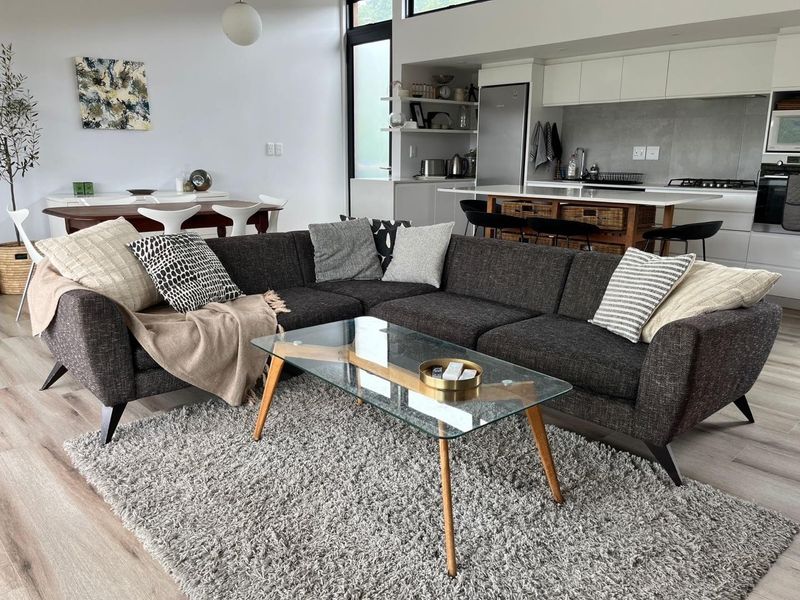 Modern open-plan living area featuring a sleek kitchen with island, high ceilings, and light-toned laminate flooring, creating a bright and spacious atmosphere.
