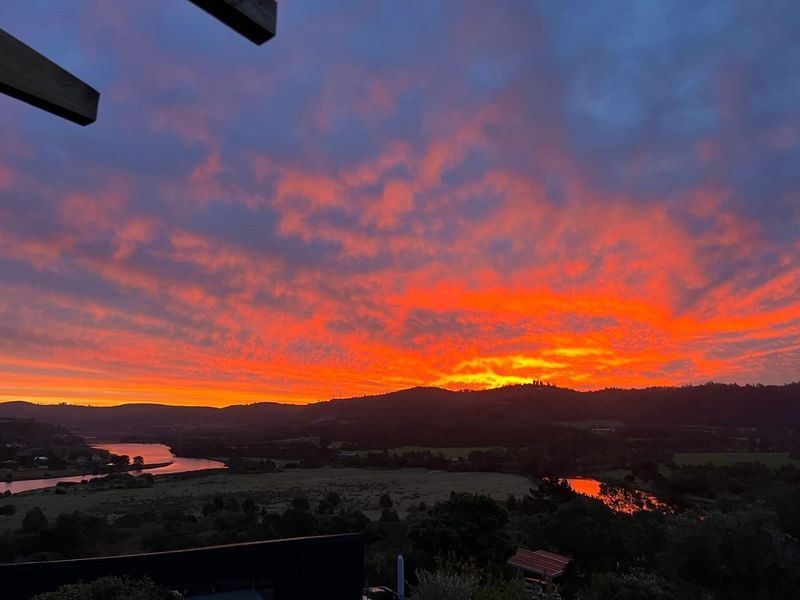 A stunning sunset view overlooking the river, valley, and surrounding hills, showcasing the property's scenic landscape and natural beauty.