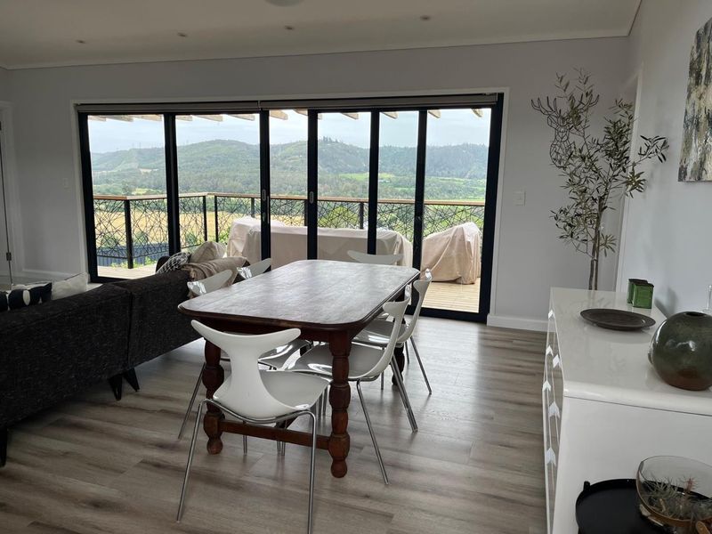 Spacious open-plan living and dining area featuring modern laminate flooring, recessed lighting, and large sliding doors opening onto a balcony with scenic views.