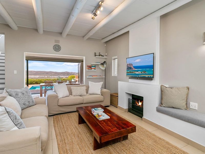 Bright living room featuring an exposed beam ceiling, a cozy fireplace, built-in bench seating, and large sliding doors opening to a patio with pool views.