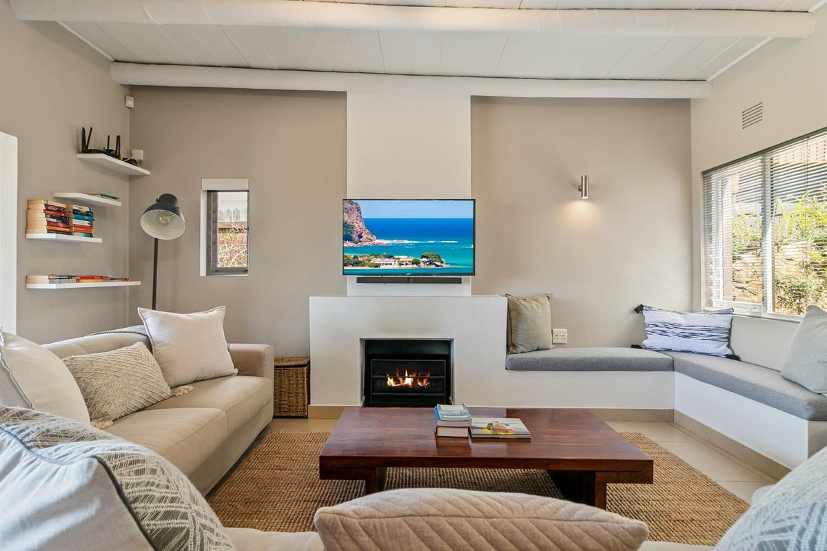 A cozy living room featuring a built-in fireplace, integrated bench seating, and exposed ceiling beams, creating a warm and inviting atmosphere.