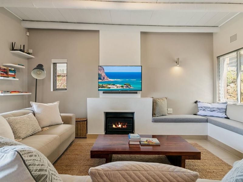 A cozy living room featuring a built-in fireplace, integrated bench seating, and exposed ceiling beams, creating a warm and inviting atmosphere.