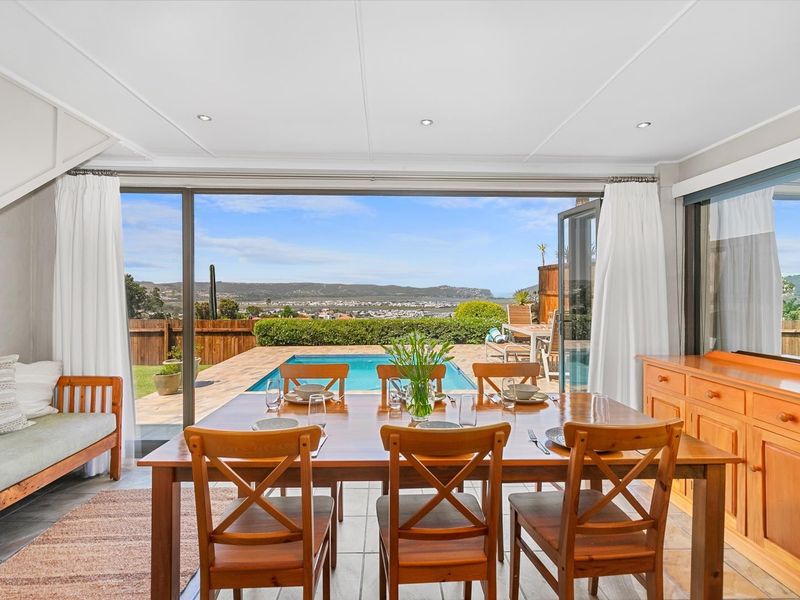 Bright dining area featuring large sliding glass doors that open onto a patio with a swimming pool and scenic views.