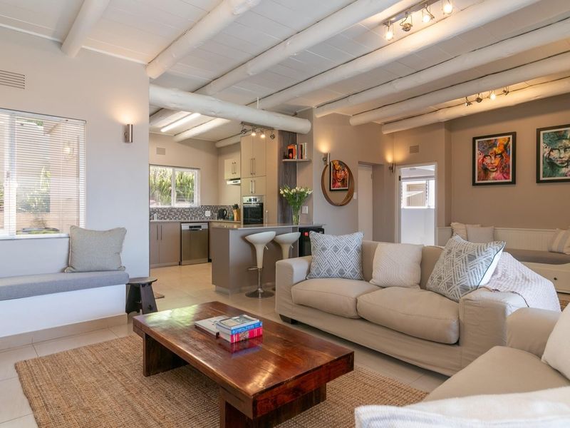 Spacious open-plan living area featuring exposed timber ceiling beams, a modern kitchen with built-in cabinetry, and a cozy built-in window seat.