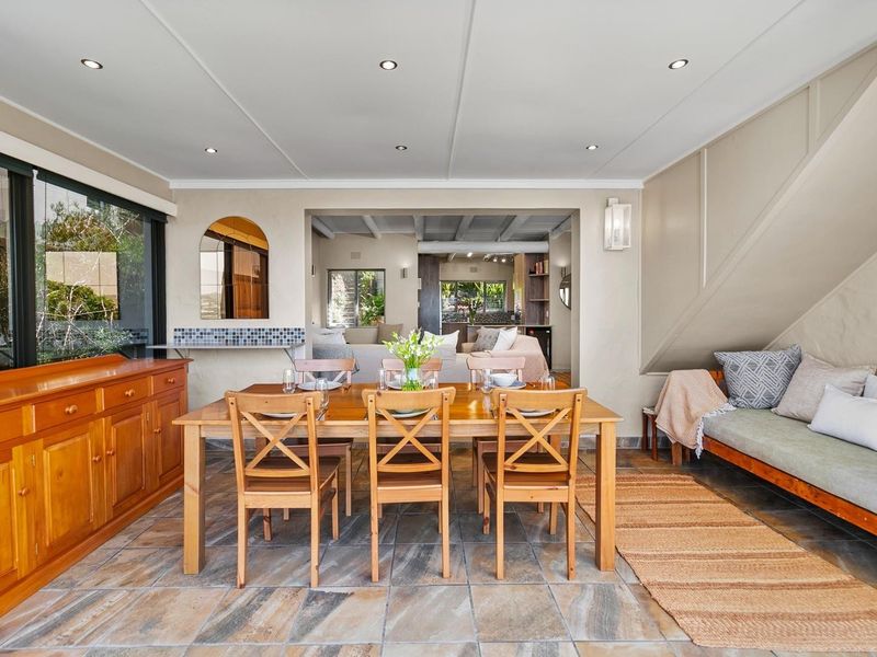 A spacious dining area featuring tiled flooring, recessed lighting, and a built-in wall niche, with an open-plan flow into the adjacent living space.