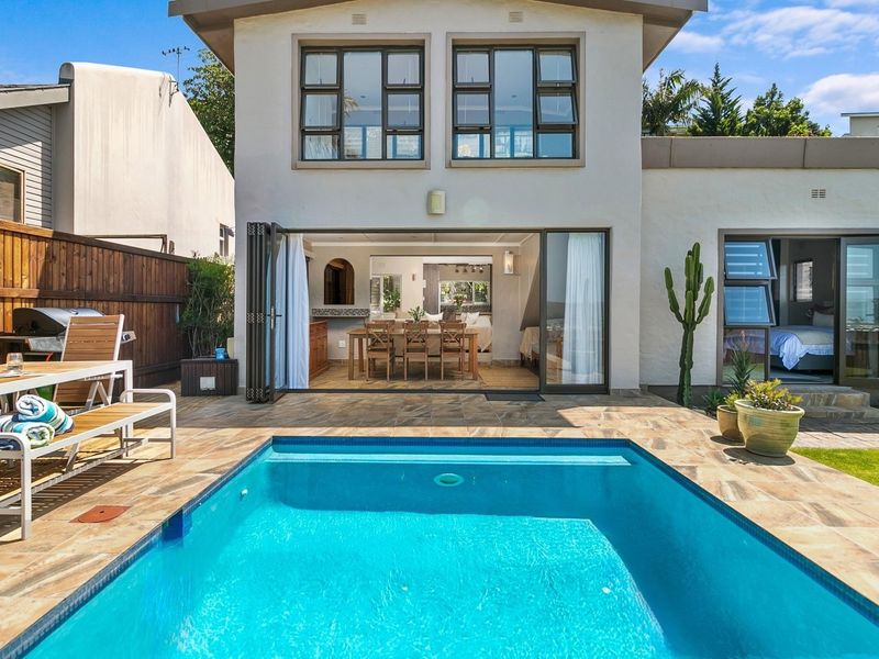 Rear exterior view featuring a swimming pool, tiled patio area, and bi-fold doors providing seamless indoor-outdoor flow to the living space.