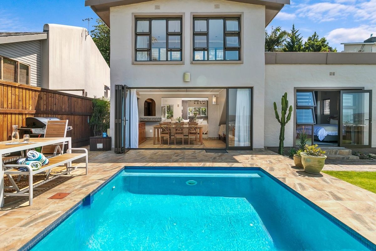 Rear exterior view featuring a swimming pool, tiled patio area, and bi-fold doors providing seamless indoor-outdoor flow to the living space.