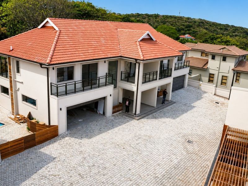 Aerial view of a multi-level townhouse complex featuring terracotta tiled roofs, paved driveway, and balcony areas under construction.