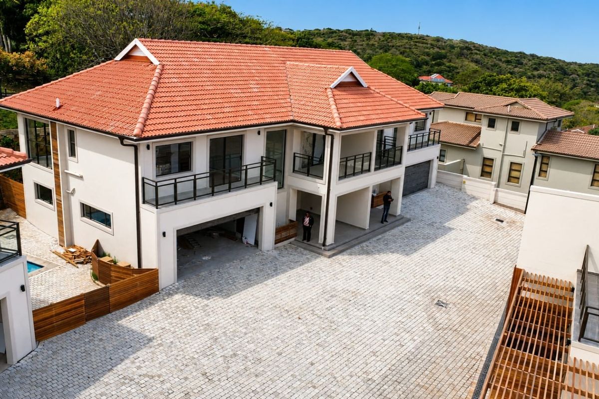 Aerial view of a multi-level townhouse complex featuring terracotta tiled roofs, paved driveway, and balcony areas under construction.