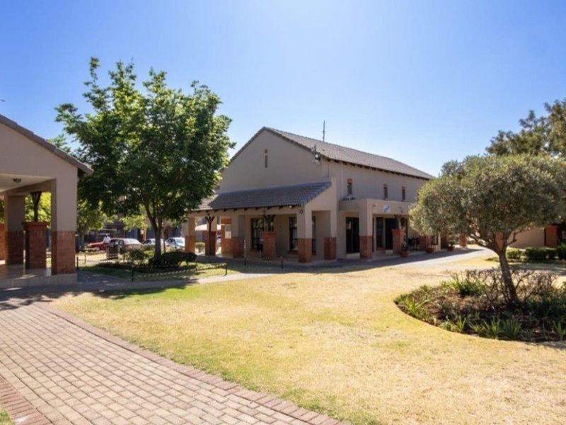 A well-maintained exterior view of the apartment complex featuring a paved walkway, covered patio areas, and landscaped garden space.