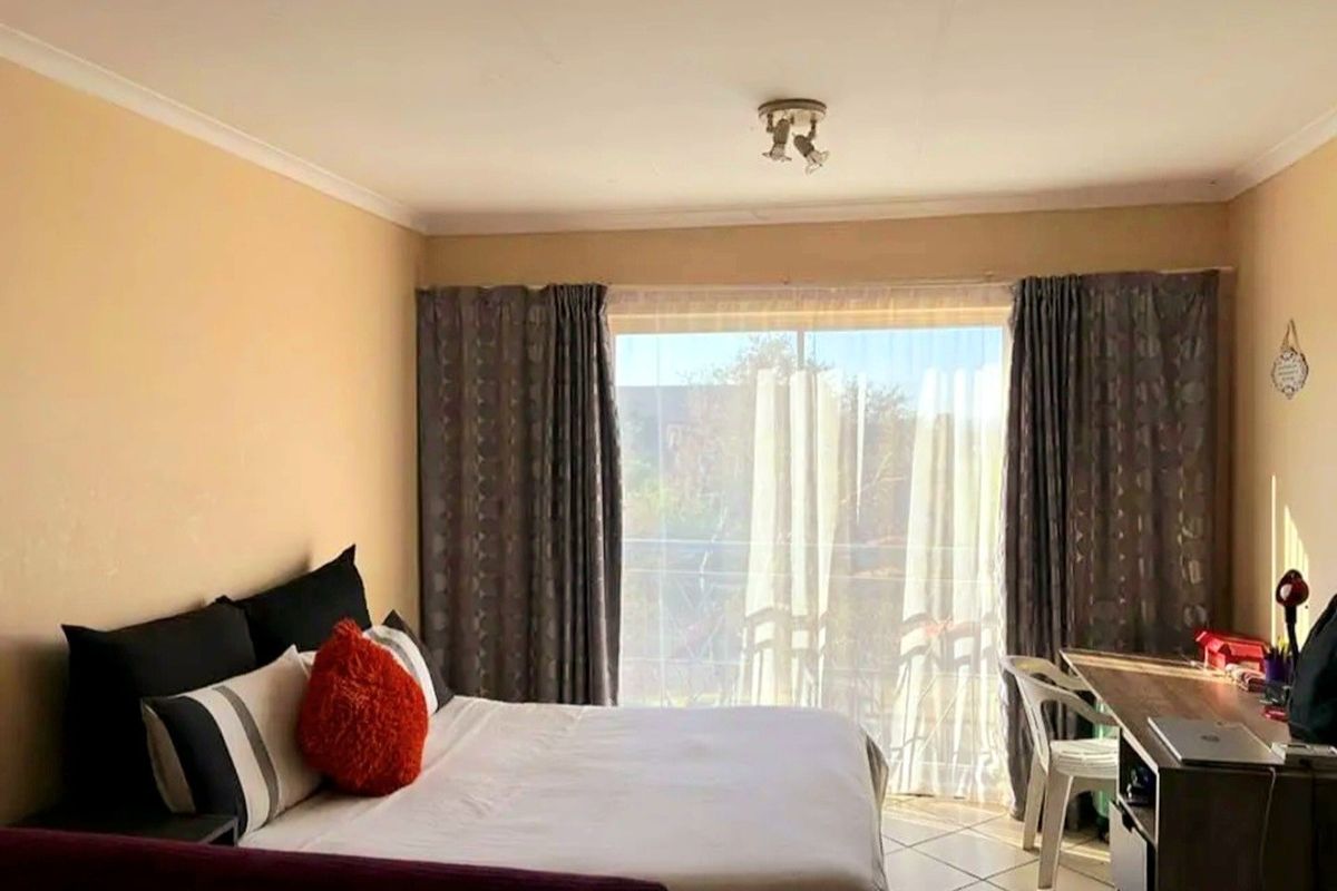 A bedroom featuring tiled flooring and a large sliding glass door providing natural light and access to an outdoor area.
