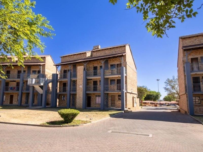 Exterior view of a multi-story apartment complex featuring face brick construction, paved driveway access, and private balconies.