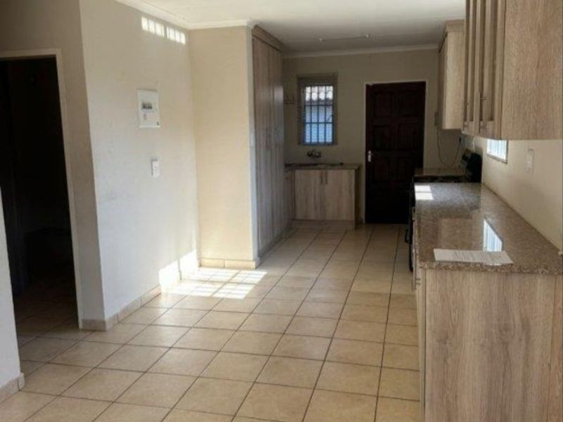 A functional kitchen featuring light wood-finish cabinetry, granite countertops, and tiled flooring. The space is vacant and ready for personalization.