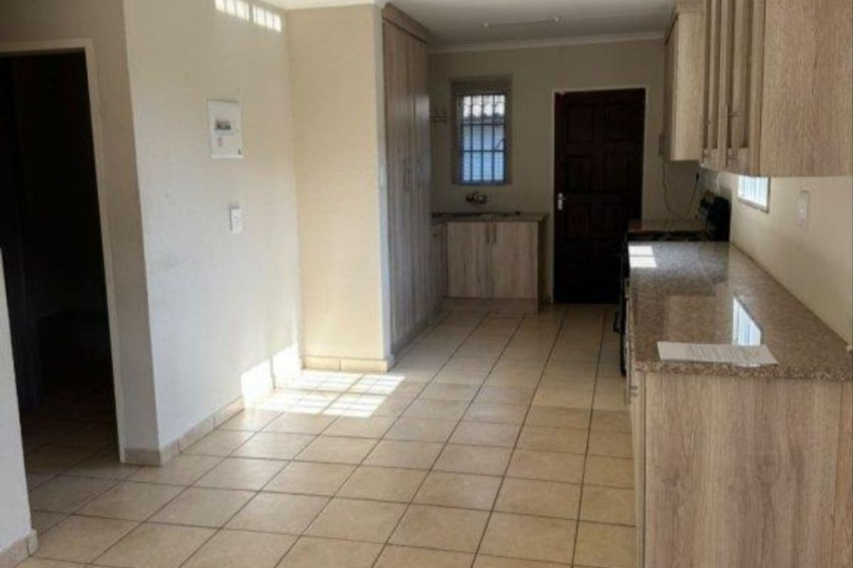 A functional kitchen featuring light wood-finish cabinetry, granite countertops, and tiled flooring. The space is vacant and ready for personalization.