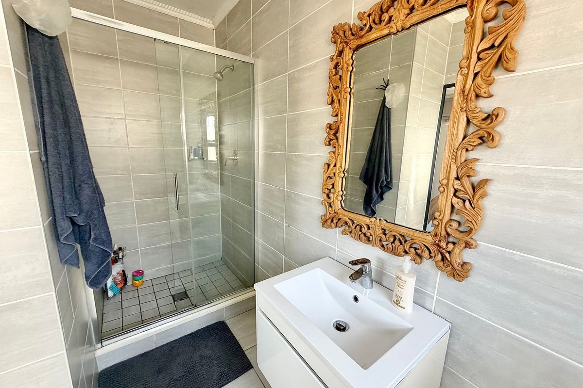 A modern bathroom featuring a glass-enclosed shower, neutral wall tiling, and a contemporary vanity basin with a mixer tap.