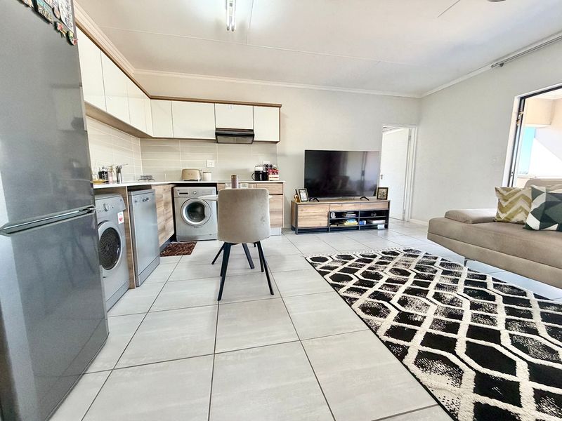 Modern open-plan living area featuring a contemporary kitchen with built-in cabinetry, tiled flooring, and seamless integration with the lounge space.