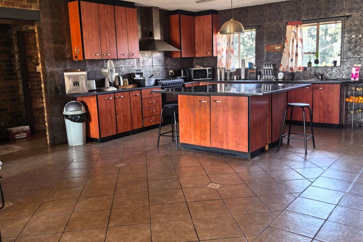 Spacious kitchen featuring a central island, built-in cabinetry, gas stove with extractor fan, and tiled flooring throughout.