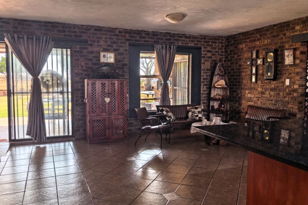 Spacious living area featuring exposed brick walls, ceramic tiled flooring, and large sliding glass doors providing access to the exterior.