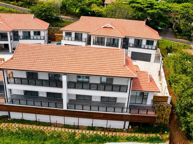 Aerial view of a modern townhouse complex featuring terracotta tiled roofs, expansive timber decking, and private balconies.