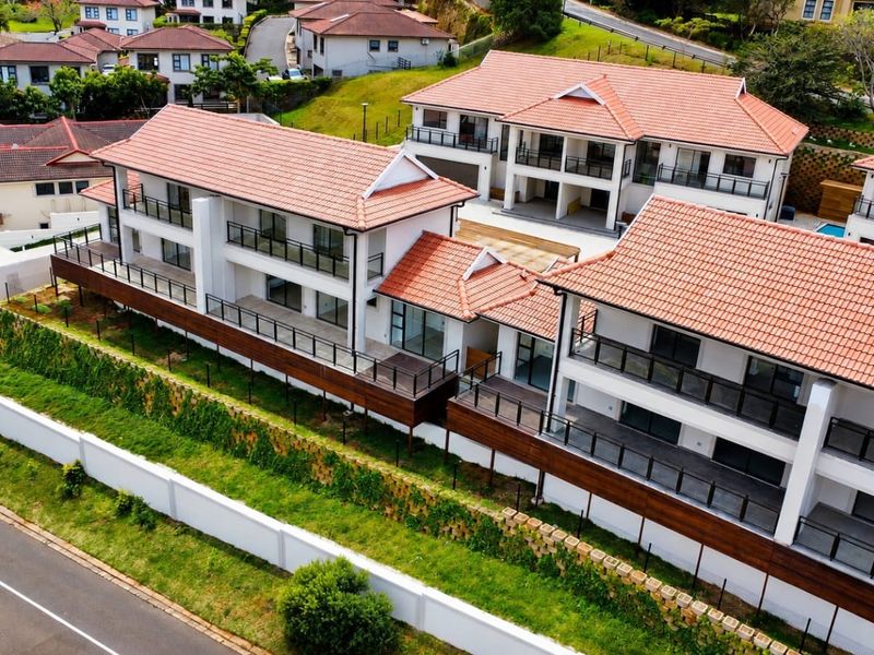 Aerial view of a modern townhouse complex featuring terracotta tiled roofs, private balconies with glass balustrades, and timber decking.