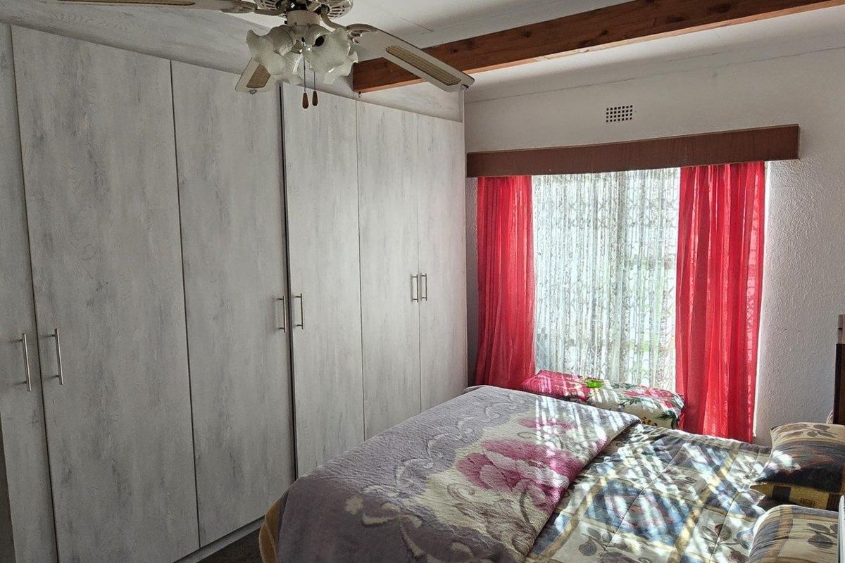 A bedroom featuring built-in cupboards, a ceiling fan, and an exposed timber beam detail.
