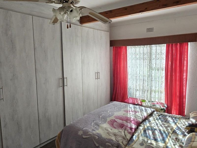A bedroom featuring built-in cupboards, a ceiling fan, and an exposed timber beam detail.