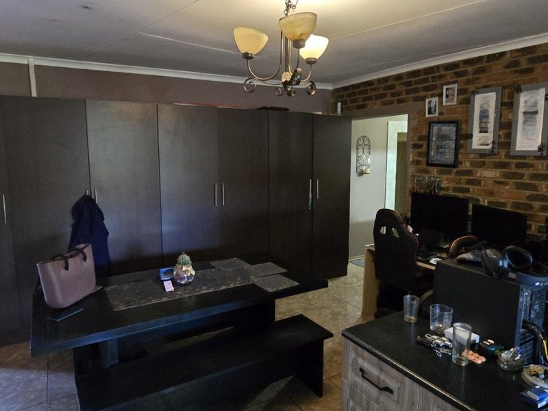 Living area featuring exposed brick wall, tiled flooring, and extensive built-in cabinetry providing ample storage space.