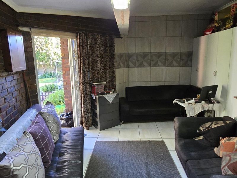 Living room featuring exposed brick walls, tiled flooring, and direct access to the garden through a sliding glass door.