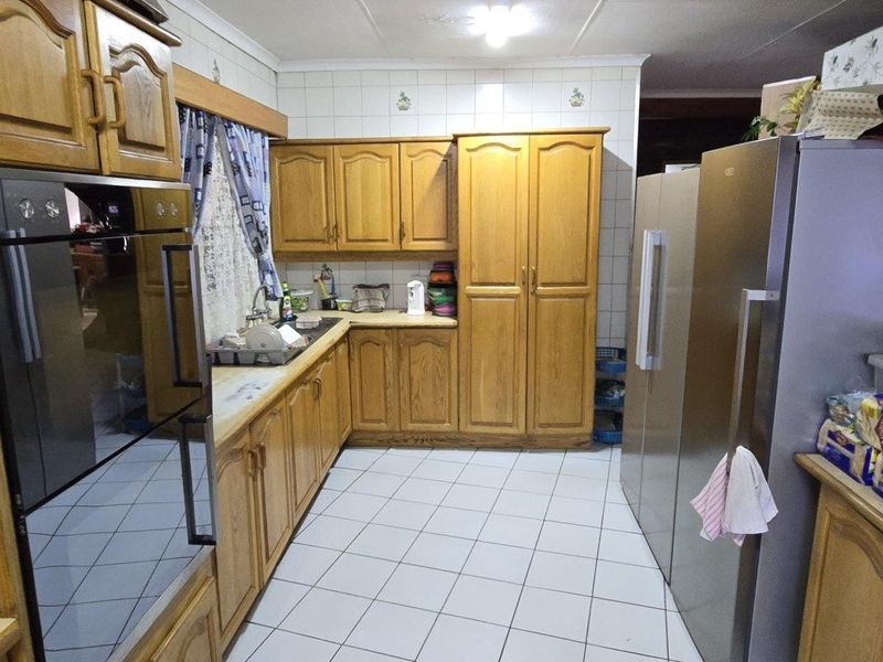 A functional kitchen featuring traditional wooden cabinetry, tiled flooring, a built-in oven, and ample counter space for meal preparation.