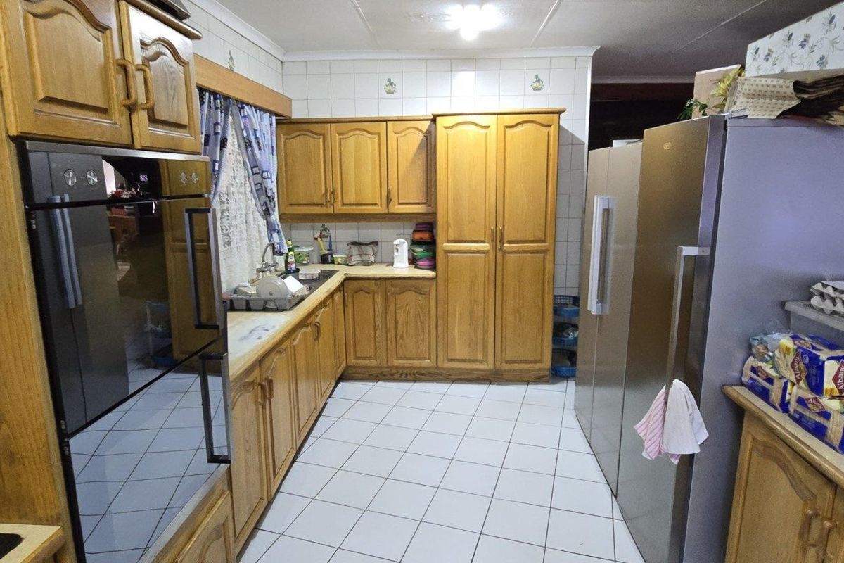 A functional kitchen featuring traditional wooden cabinetry, tiled flooring, a built-in oven, and ample counter space for meal preparation.