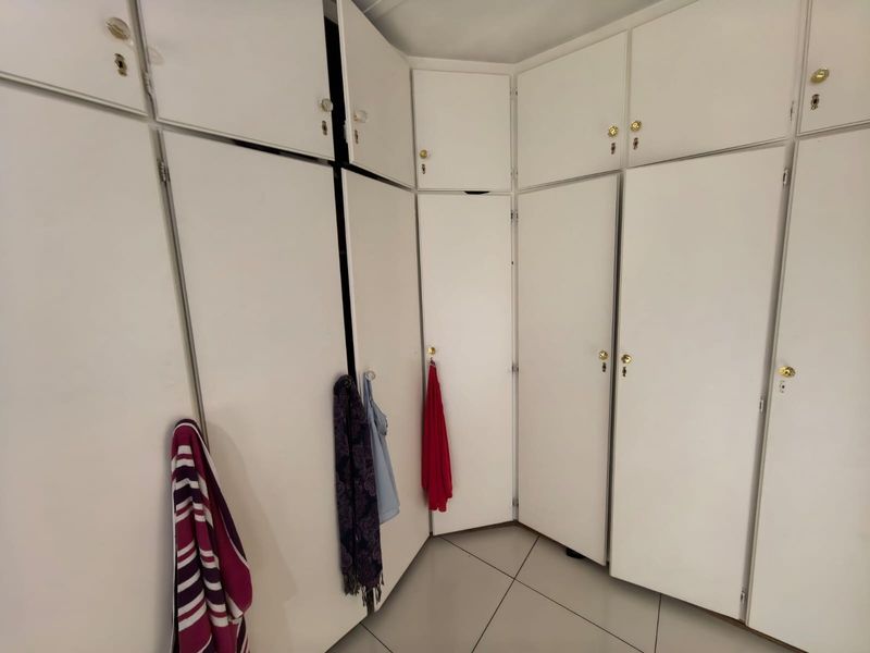 A bedroom featuring extensive white built-in cupboards and tiled flooring, offering ample storage space.