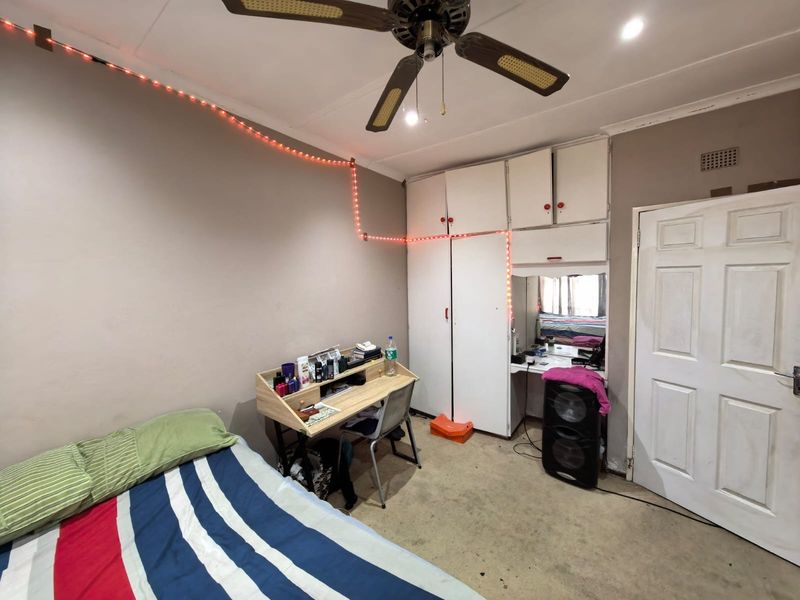 A bedroom featuring built-in cupboards with an integrated vanity area, a ceiling fan, and carpet flooring.