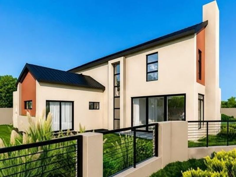 Modern two-story residential home featuring a contemporary architectural design with a metal roof, stucco finish, and large sliding glass doors opening to the garden.