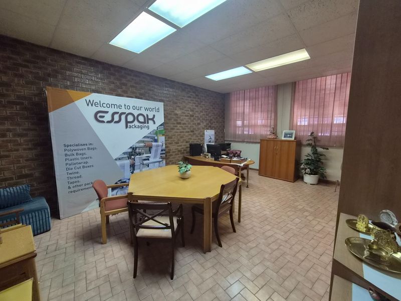 A functional office space featuring exposed brick walls, tiled flooring, and suspended ceiling lighting, suitable for administrative or industrial business operations.