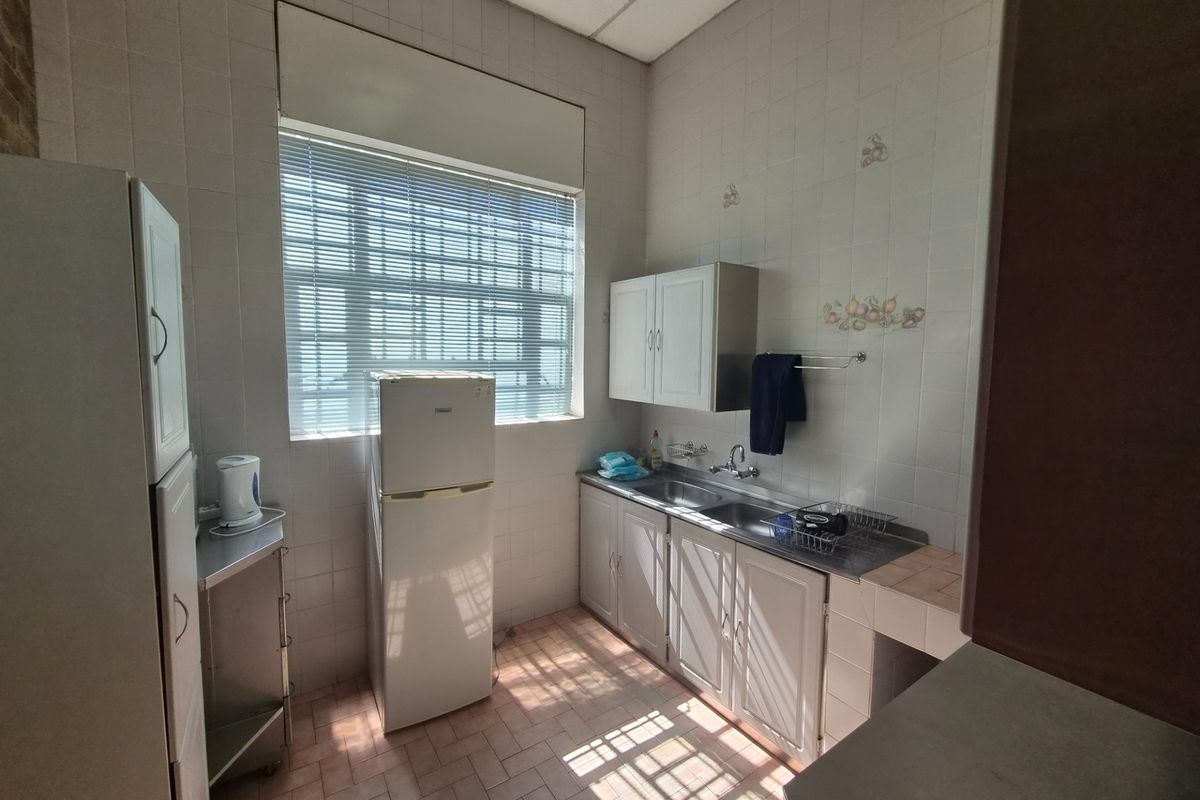 A functional industrial-style kitchen featuring built-in cabinetry, a double stainless steel sink, and tiled finishes throughout.