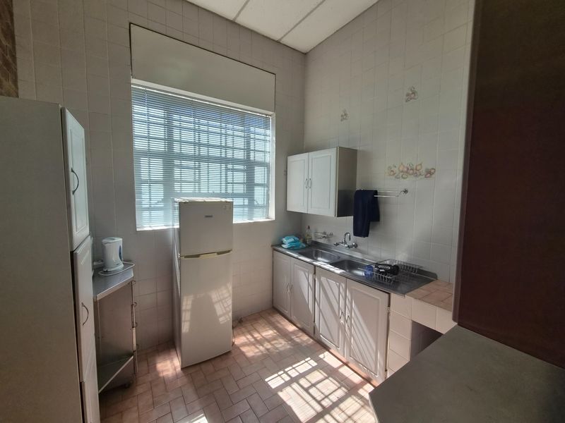 A functional industrial-style kitchen featuring built-in cabinetry, a double stainless steel sink, and tiled finishes throughout.