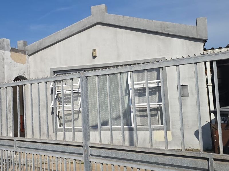 Front elevation of a residential property featuring a metal security gate and concrete facade with visible signs of exterior wear.