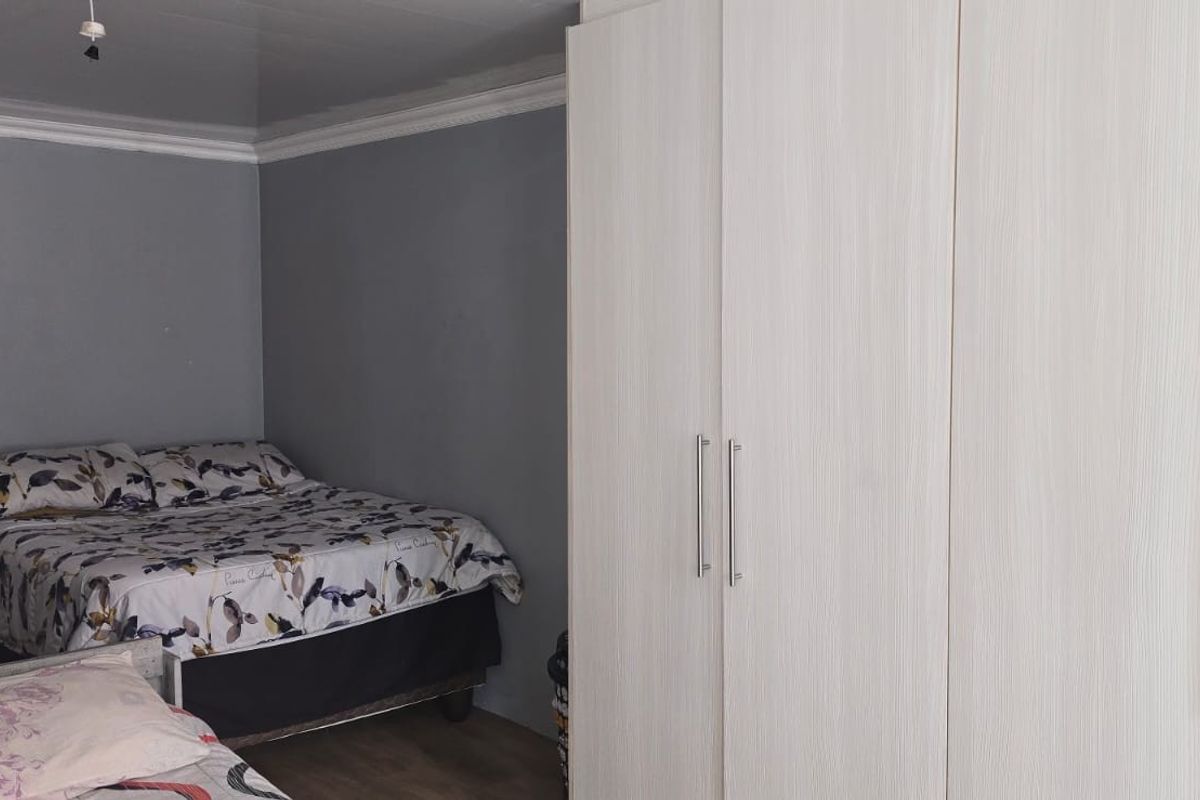 A bedroom featuring grey walls, crown molding, and a large built-in wardrobe with light wood-grain finish doors.