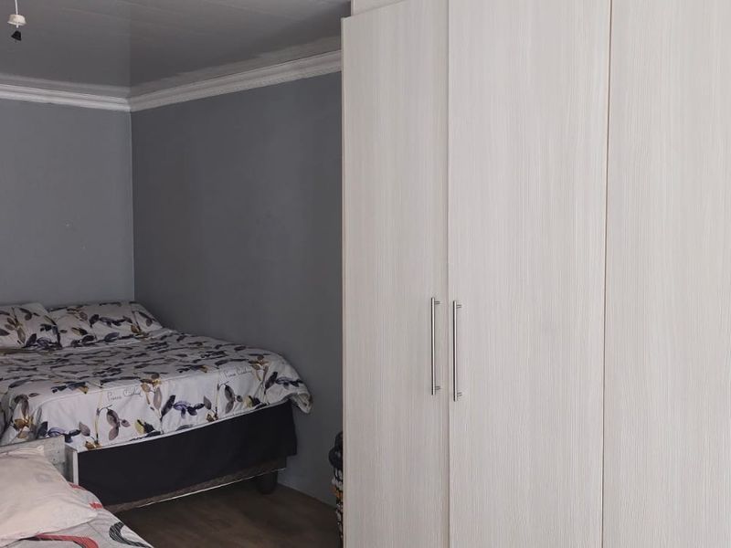 A bedroom featuring grey walls, crown molding, and a large built-in wardrobe with light wood-grain finish doors.