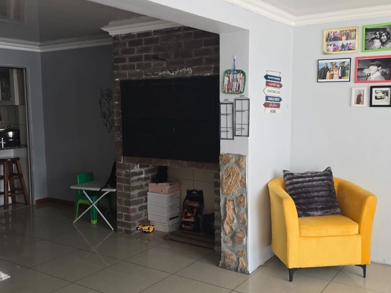 Open plan living area featuring a brick fireplace with stone accents, tiled flooring, and a connected kitchen with granite countertops.