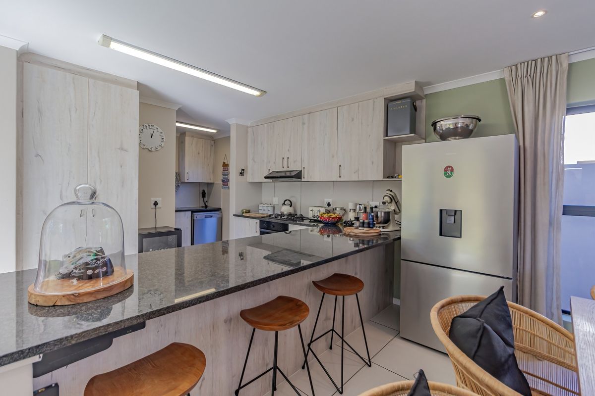 Modern kitchen featuring granite countertops, ample built-in cabinetry, and a breakfast bar, seamlessly integrated with the living area.