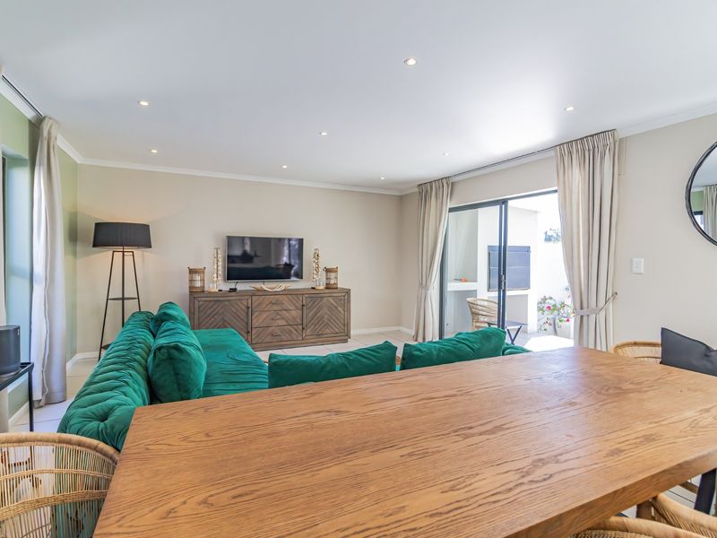 Spacious open-plan living and dining area featuring recessed downlights, neutral wall finishes, and large sliding glass doors providing access to the outdoor patio.