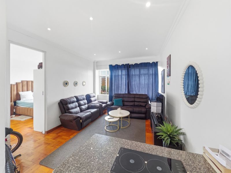 Open-plan living area featuring parquet flooring, recessed lighting, and a kitchen section with granite countertops and an integrated electric hob.