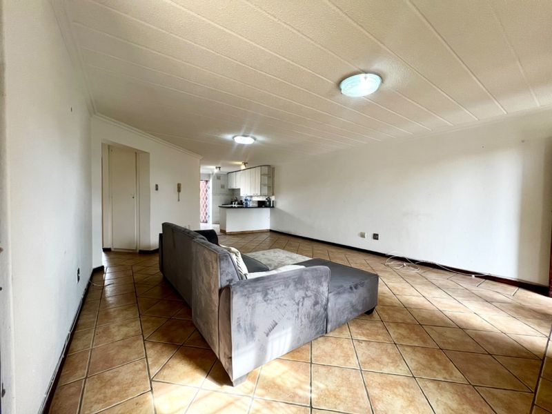 Open-plan living area featuring tiled flooring and a functional kitchen space with built-in cabinetry and countertops.