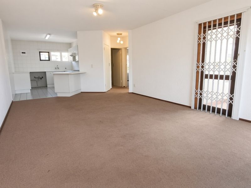 Spacious open-plan living area featuring a functional kitchen with built-in cabinetry and direct access to a balcony through a secure gate.