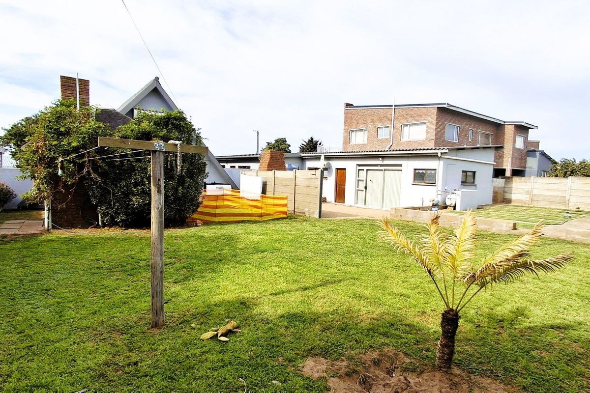 A spacious rear garden featuring a lawn, paved patio area, and boundary walling, providing a functional outdoor space for the property.