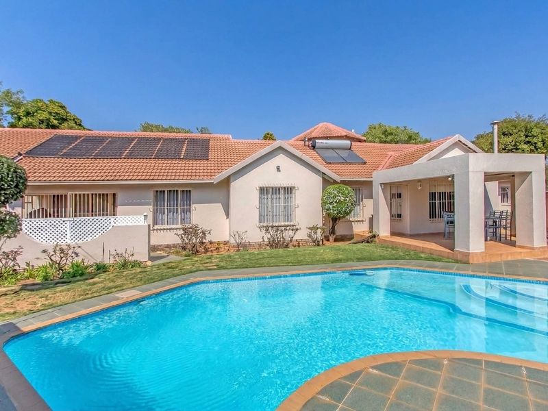 Rear view of the house featuring a swimming pool, covered patio, and roof-mounted solar panels and water heating system.