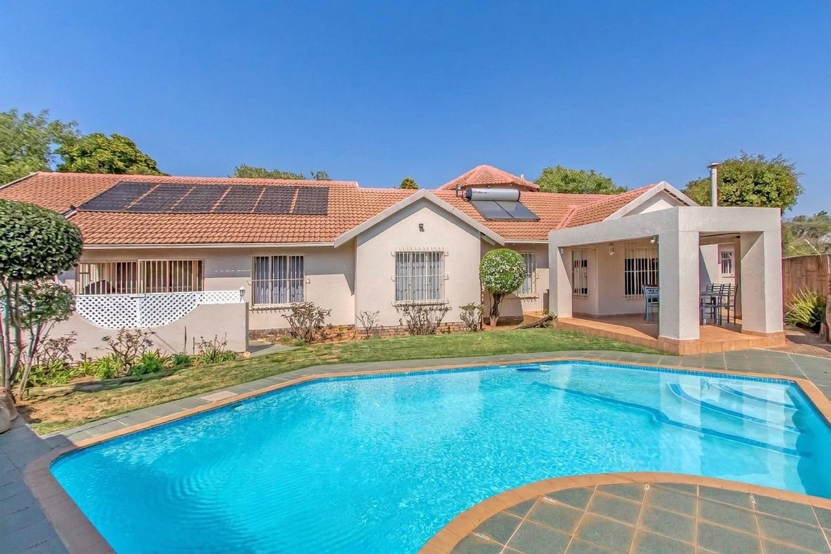 Rear view of the house featuring a swimming pool, covered patio, and roof-mounted solar panels and water heating system.