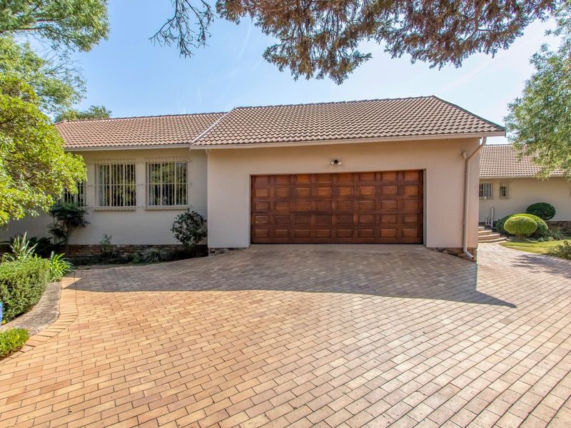 Front exterior view of the house featuring a paved driveway, a double wooden garage door, and tiled roof.