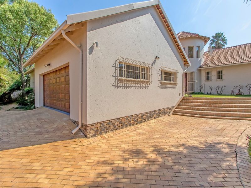 Front exterior view of the property featuring a paved driveway, garage access, and tiled steps leading to the main entrance.